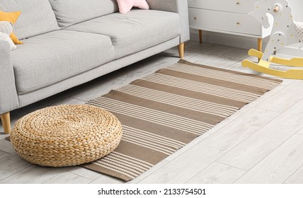 Stylish carpet and ottoman on wooden floor in room interior