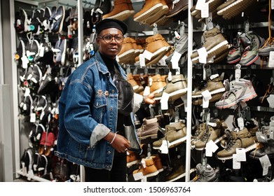 Stylish Casual African American Man At Jeans Jacket And Black Beret At Clothes Store Trying New Footwear.