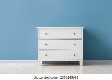 Stylish chest of drawers near color wall in room