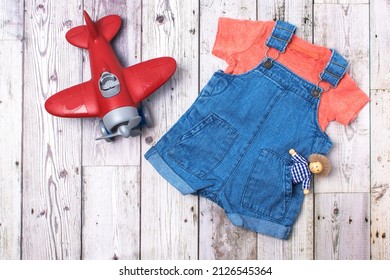 Stylish children's clothing and a children's plane on a gray wooden background. View from above. copy space