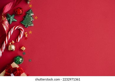 Stylish christmas gift, candy cane, confetti and decorations border on red background, flat lay. Modern season's greetings card, space for text. Merry Christmas and Happy Holidays! Festive banner - Powered by Shutterstock