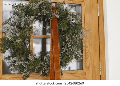 Stylish christmas rustic wreath with ribbon hanging on front doors, close up. Modern house entrance or porch decoration for winter holiday. Merry Christmas and Happy holidays - Powered by Shutterstock