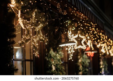 Stylish christmas star illumination and spruce branches in golden lights in evening, fairytale decoration. Atmospheric magic time. Christmas festive decor for winter holidays in city street - Shutterstock ID 2063275760