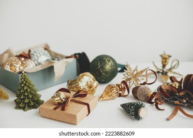 Stylish christmas vintage ornaments, gift, ribbon, scissors on rustic white table. Merry Christmas! Wrapping present aesthetic. Preparation for winter holidays, atmospheric time. Moody banner - Powered by Shutterstock