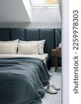 Stylish composition of bedroom interior design with grey bed, beige bedclothes, wooden night table and elegant personal accessories. Details. Template.