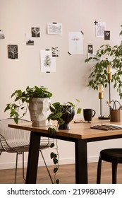 Stylish composition of cozy office interior with black chair, wooden table, plants, office accessories, post cards, decorations and personal accessories. Modern home decor. Template.	
