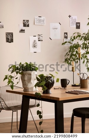 Stylish composition of cozy office interior with black chair, wooden table, plants, office accessories, post cards, decorations and personal accessories. Modern home decor. Template.	
