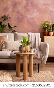 Stylish composition of creative spacious living room interior with plants, sofa, coffee table, rattan chest of drawers and stylish accessories. Botanical space of a cozy room. Brown walls. Template. 