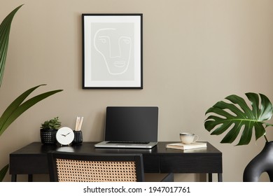 Stylish Composition Of Home Office Interior With Black Wooden Desk, Chair, Tropical Flower In Vase, Laptop, Mock Up Poster Frame, Cup Of Coffee, Clock And Elegant Office Accessories. Template.