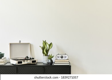Stylish composition of living room interior with design black commode, plants, book,  vinyl recorder, decoration and elegant personal accessories.  Copy space. Modern home decor.