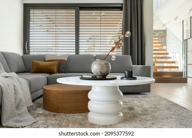 Stylish composition of living room interior with corner beige sofa, coffee table, carpet on the floor and minimalist accessories. Template.