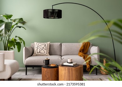 The stylish composition at living room interior with green wall, design gray sofa, coffee table, dark lamp and elegant personal accessories. Beige pillow and plaid. Cozy apartment. Template.  - Shutterstock ID 2173595381