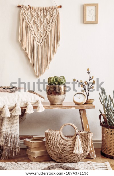 Stylish composition of living room interior with\
mock up frame, wooden bench, pillow, plaid, woman bag, books,\
cacti, macrame, plant, decortaion and elegant personal accessories\
in modern home decor.