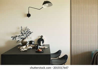 Stylish composition of modern small dining space interior. Black table, black designed lamp, black and light wooden kitchen and dining accessories. Neutral walls. Minimalistic masculine concept. 