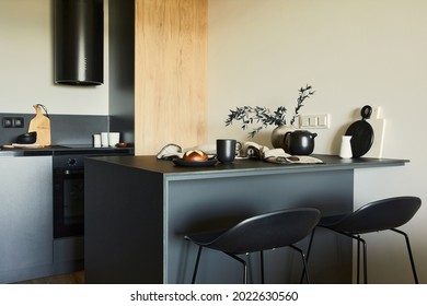 Stylish composition of modern small dining space interior. Black kitchen island and dining accessories. Neutral walls. Minimalistic masculine concept. Details. Template.