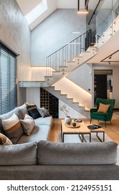 Stylish Composition Of Stairs In Living Room Interior. Grey Sofa, Green Velvet Armchair, Coffee Table And Minimalist Personal Accessories. Modern Home Decor. Template.