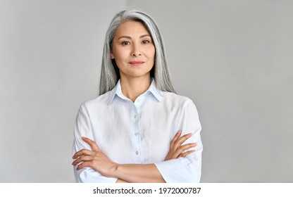 Stylish confident adult 50 years old Asian female psychologist standing arms crossed looking at camera at gray background  Portrait sophisticated grey hair woman advertising products   services 
