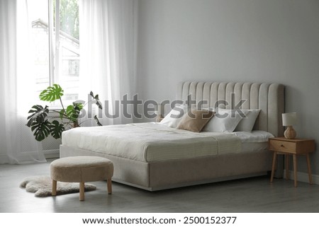 Stylish contemporary bedroom interior with houseplant and comfortable bed