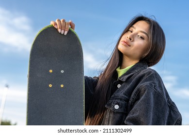 Stylish cool teen female skateboarder at skate park, asian girl portrait