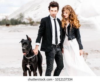 Stylish couple with big dog in desert. Concept of successful relationship, style and happy moments. Fashion wedding photography