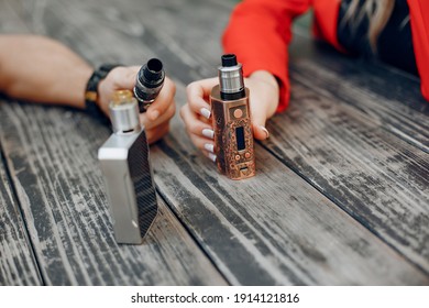 Stylish couple in a city. Two people use the electronic cigarette