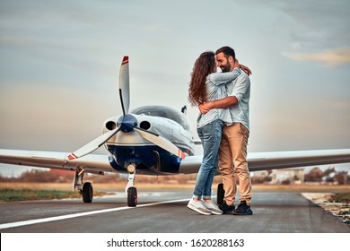 Stylish Couple Standing Near A Plane At The Airport. Honeymoon. Full Length