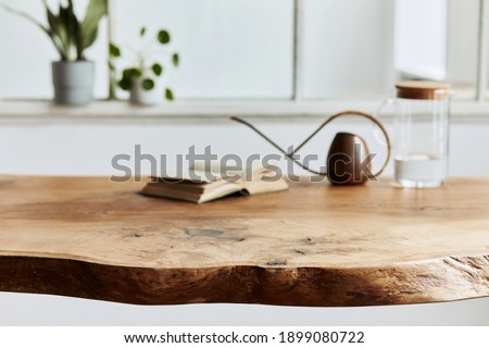 Stylish and cozy compositon of craft oak wooden table with chairs, watering can, glassy jug and modern floor in beautiful interior of design home. Template.