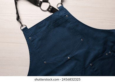 Stylish dark blue apron on white wooden table, top view. Mockup for design