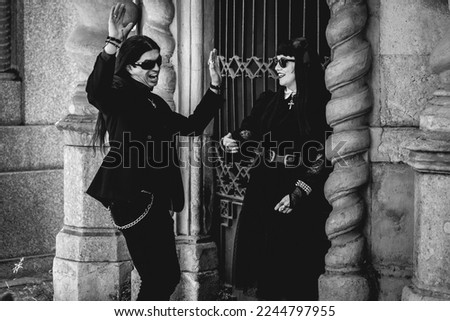 Stylish dark gothic couple in large ancient abandoned mausoleum with neoclassical style in a sunny day (in black and white)