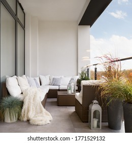 Stylish Decorated Balcony With Rattan Outdoor Furniture, Bright Pillows, Fluffy Blanket And Plants