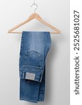 Stylish denim blue jeans hanging on a wooden hanger. These denim blue jeans are perfect for casual wear. Ideal for unisex, these blue denim jeans fashion casual style. perfect for apparel streetwear