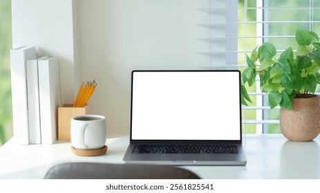 Stylish desk arrangement showcasing a laptop, a cozy coffee mug, and a lush green plant, ideal for a productive and aesthetically pleasing work environment. - Powered by Shutterstock