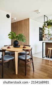 Stylish dining room interior design with dining table. Workspace with kitchen accessories on the background. Creative walls, white and wooden pannels. Minimalistic style an plant love concept.  - Shutterstock ID 2154168981
