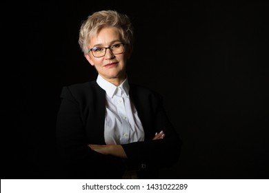 Stylish Elderly Woman In Glasses And Black Jacket On A Black Background	