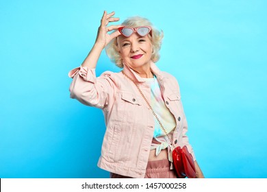 Stylish elderly woman in sunglasses and trendy clothes is smiling and looking at the camera. happiness, beuty, free time, spare time