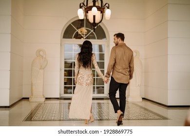 Stylish elegant couple in golden dress and suit walk to the entrance of restaurant