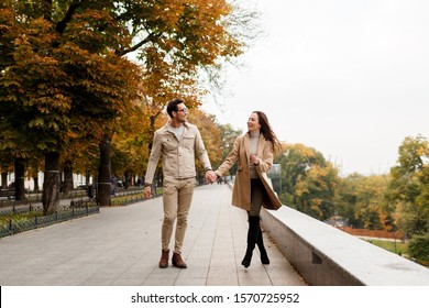 Stylish elegant man and brunette woman walking in autumn park. Dating time. Full length.  - Powered by Shutterstock