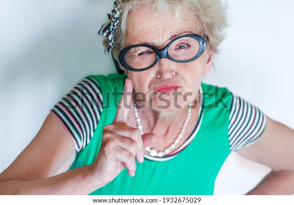 Stylish emotional elderly woman with an evil face\
waving index finger over white background. Concept protest and\
objection of an old woman. Morality and censure. Grumpy\
grandmother. Angry\
woman