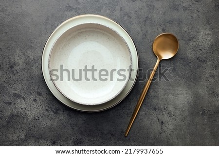 Stylish empty dishware and spoon on grey table, flat lay