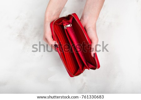 Stylish empty female red purse in female hands on a white texture