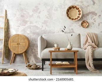 The Stylish Ethnic Composition At Living Room Interior With Grey Sofa, Colorful Wicker, Rattan Sideboard, Bench And Elegant Personal Accessories. Grey Concrete Wall. Cozy Apartment. Home Decor. 