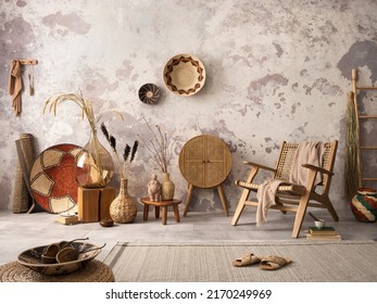 The stylish ethnic composition at living room interior with design brown armchair, colorful baskets, rattan sideboard and elegant personal accessories. Grey concrete wall. Cozy apartment. Home decor. 