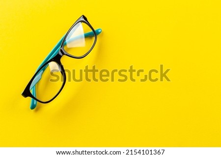 Stylish eyeglasses over yellow background. Glasses selection, eye test, vision examination at optician, fashion accessories concept. Top view, flat lay. Space for text.