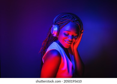 Stylish Fashion African American Teenager Model Wearing Headphones Listening Dj Music Dancing In Purple Neon Lights. Young Teen Girl Enjoy Cool Music