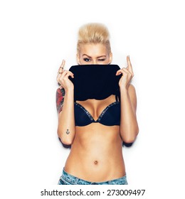 Stylish fashion blonde girl with tattoo in a black t-shirt showing his chest. Woman showing middle finger. White background, not isolated
