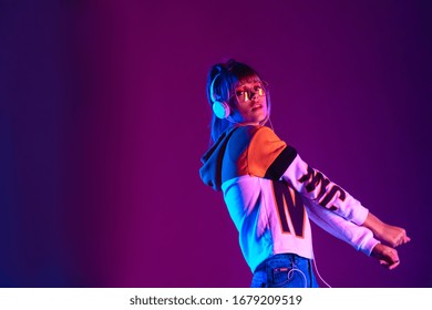 Stylish Fashion Igen Teen Hipster Pretty Girl Model Wear Eyeglasses Headphones Enjoy Listen New Trendy Dance Music Mix Look At Camera Stand At Purple Studio Background 80s Party Light, Portrait