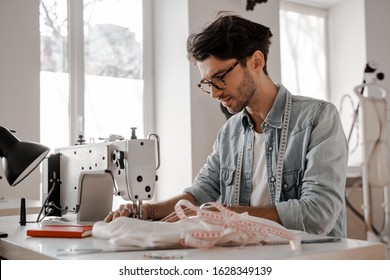 Stylish and fashionable clothes designer man sews at a sewing machine. Sewing, design work, tailoring studio, tailor, designer clothes, manufactory, in the process of creative development - Powered by Shutterstock