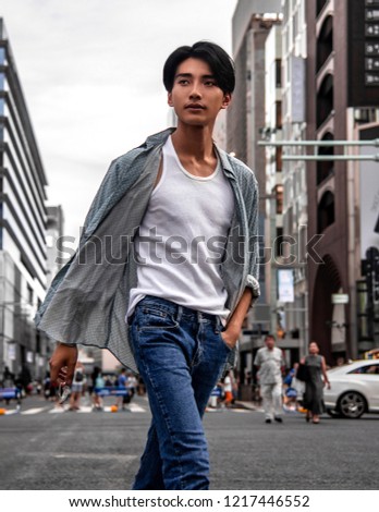 Stylish Fashionable Man Walking on a City Street. Asian Male Model Wearing casual clothes, white t-shirt, jeans, button shirt posing posing walking in the City. 