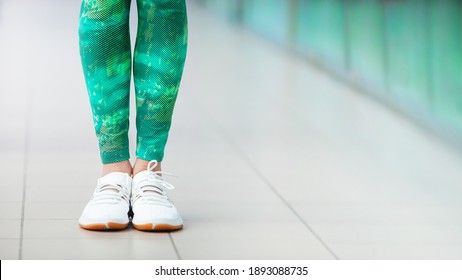 Stylish fashionable white women's leather shoes in the gum. Female legs with white sneakers on light background. Sport and lifestyle concept. Soft focus.