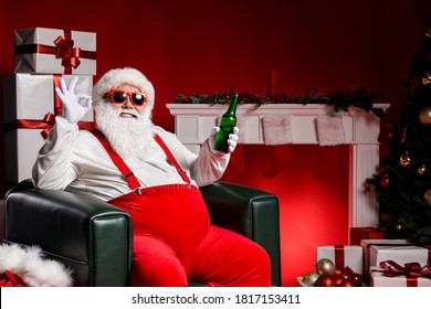 Stylish fat santa claus sit chair show ok sign hold beer have x-mas fireplace tradition present box ornament isolated over bright shine color background
